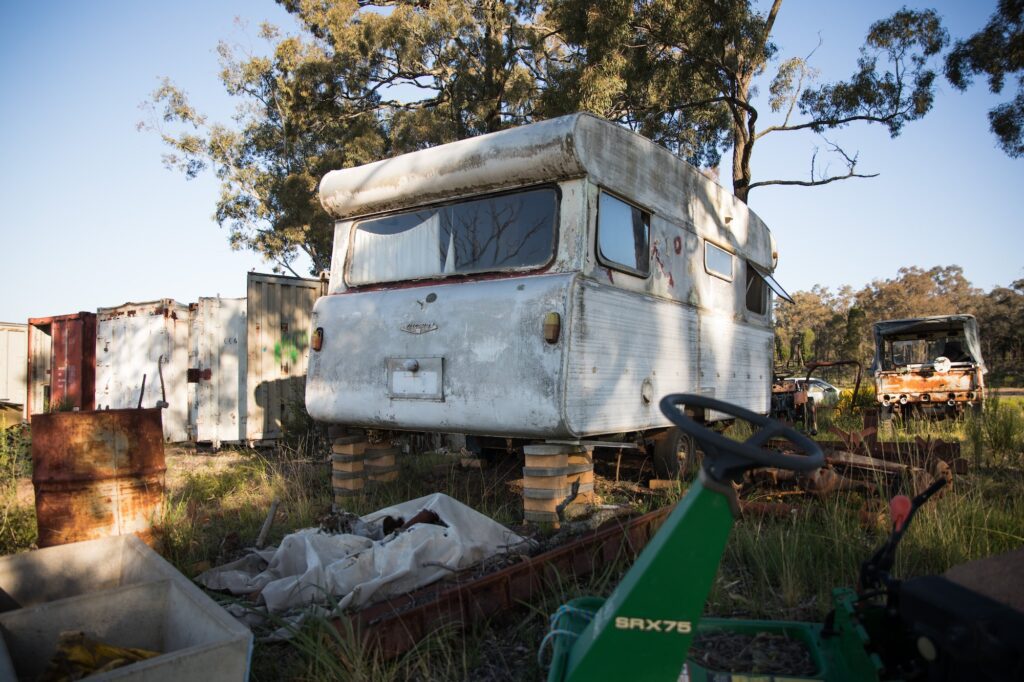 Old disused abandoned caravan on a farm at sunset